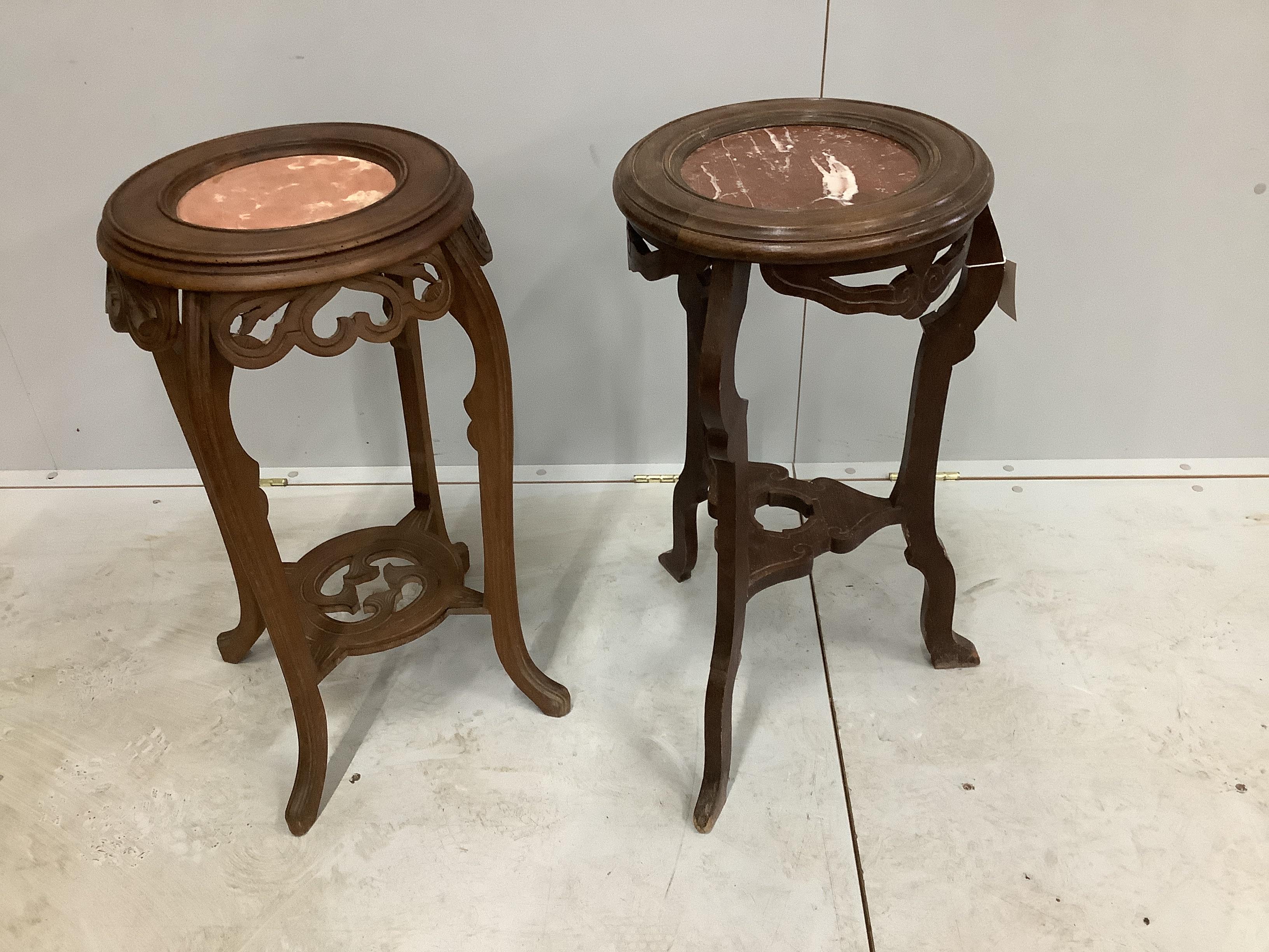 A near pair of Chinese circular rouge marble topped hardwood jardiniere stands, largest diameter 35cm, height 70cm